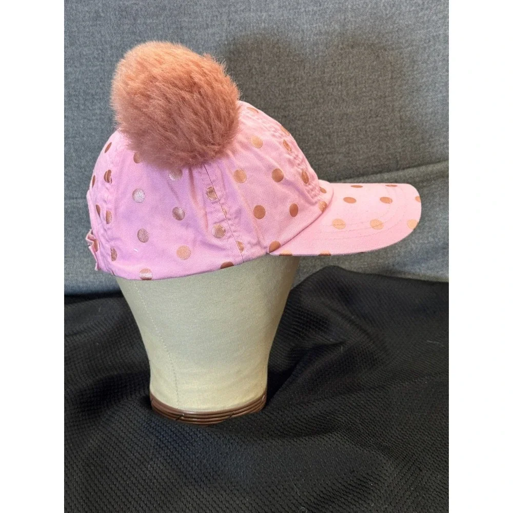 Pink polka-dot cap topped with two fluffy faux fur pom poms